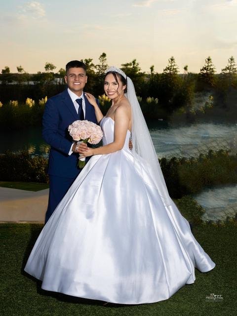 Novios con vestido de novia de satén y ramo de rosas al atardecer