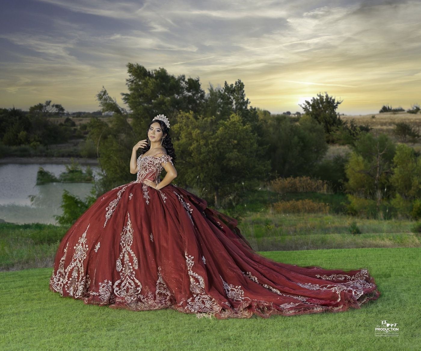 Quinceañera con vestido rojo y corona al atardecer junto a un lago