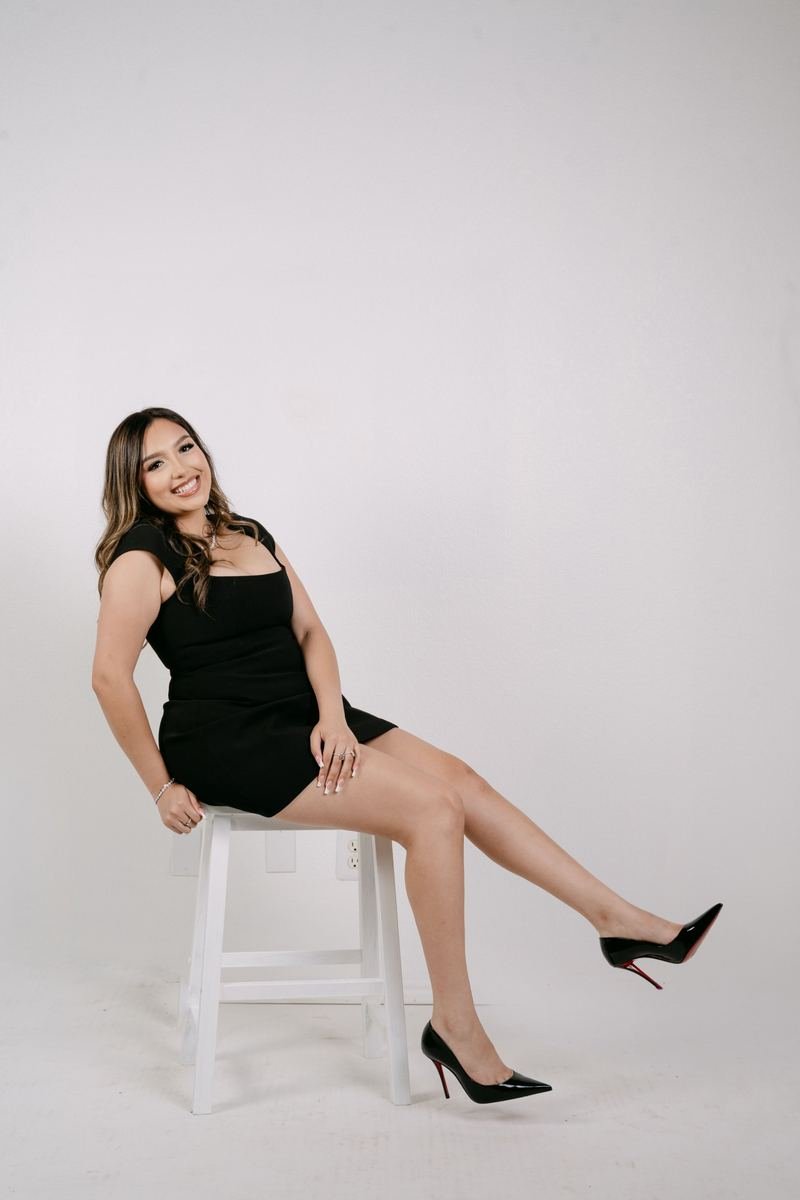 Retrato en estudio, sentada en un banco con vestido negro